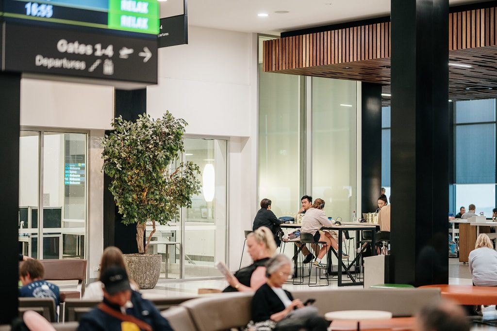 The image is of Launceston Airport. There are people waiting for their flights, reading, typing, and chatting. This is one of Drive Car Hire's main locations.