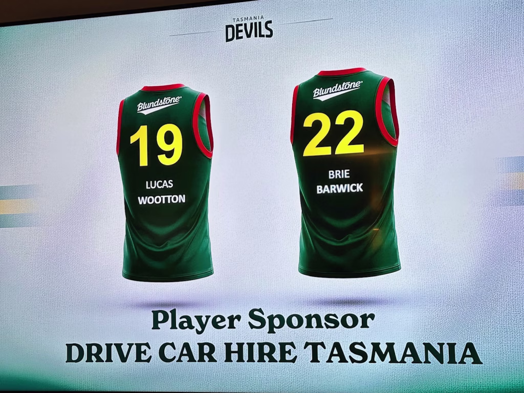 The image shows jerseys of two Tasmania Devils players: #19 Lucas Wootton of the VFL and #22 Brie Barwick of the VFLW. We see the Tasmania Devils logo above the jerseys as well as the Blundstone logo on the jerseys. Below, the text reads: "Player Sponsor, DRIVE CAR HIRE TASMANIA"