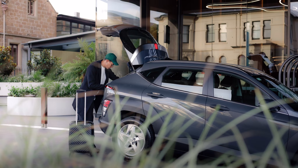 A man in a green cap with a suitcase opens the trunk of his gray Hyundai Kona in front of the DoubleTree in Hobart.

Credit Lucas Suárez
Instagram: @althaphoto