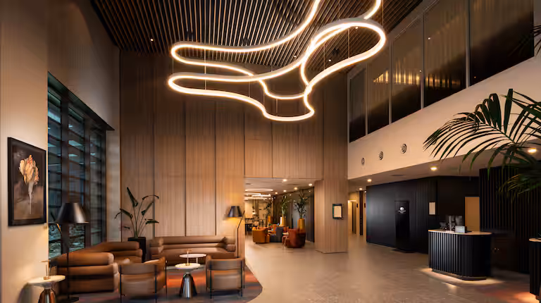 The lobby of the DoubleTree in Hobart. A modern light fixture up top, a concierge desk to the right, and a seating area to the left.