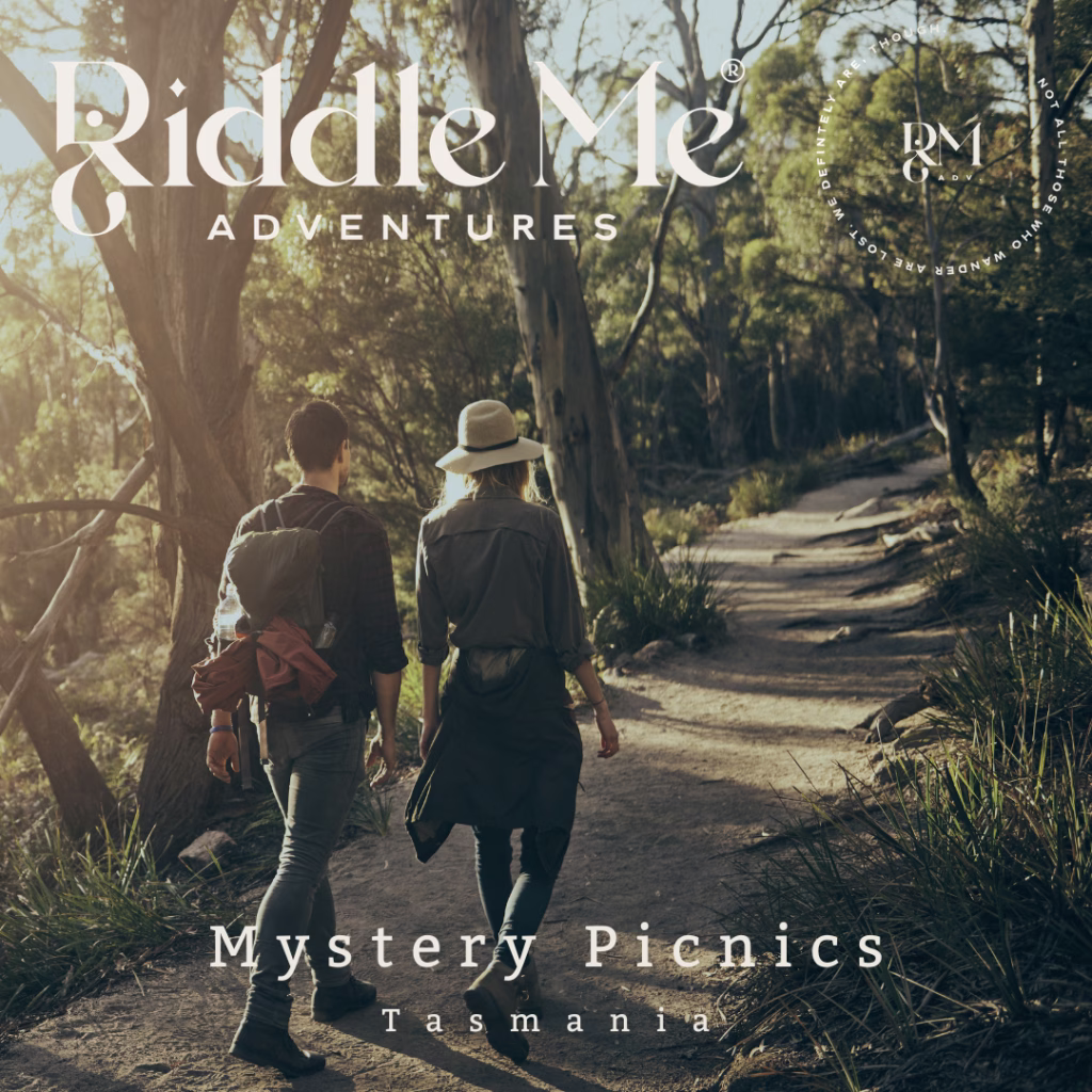 The Riddle Me Adventures Mystery Picnics Tasmania promo photo with two people walking in a forest. They have their backs to us and one has a backpack and the other a hat. The sun shines through the trees and onto the trail path.