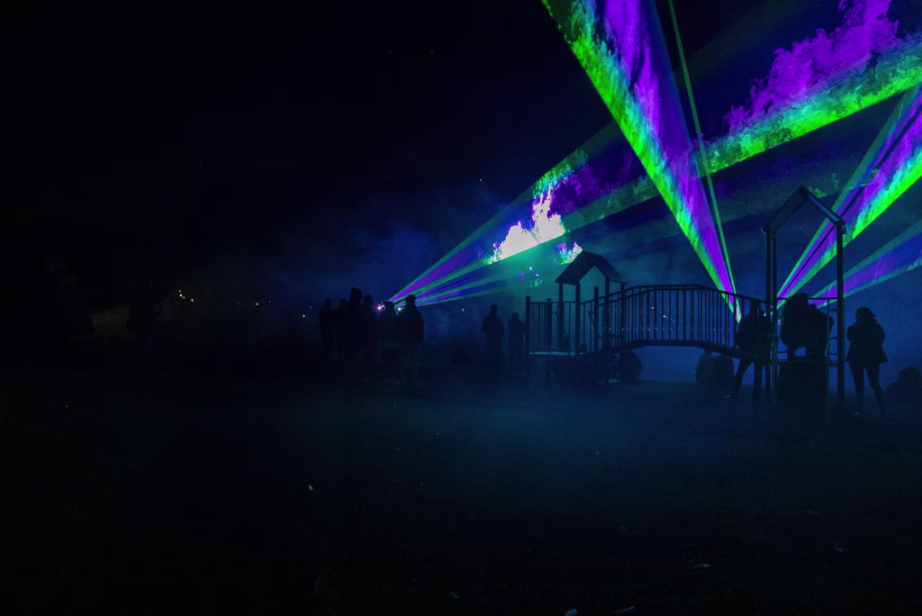 Adam Reibel - photo. Bicheno Beams laser light show emits purple and green laser art over a playground in the dark
