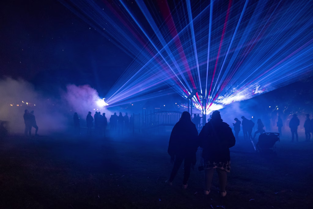 Photography: Adam Reibel
Bicheno Beams laser light show shows off blue and red beams in clouds of smoke as people stand and watch.